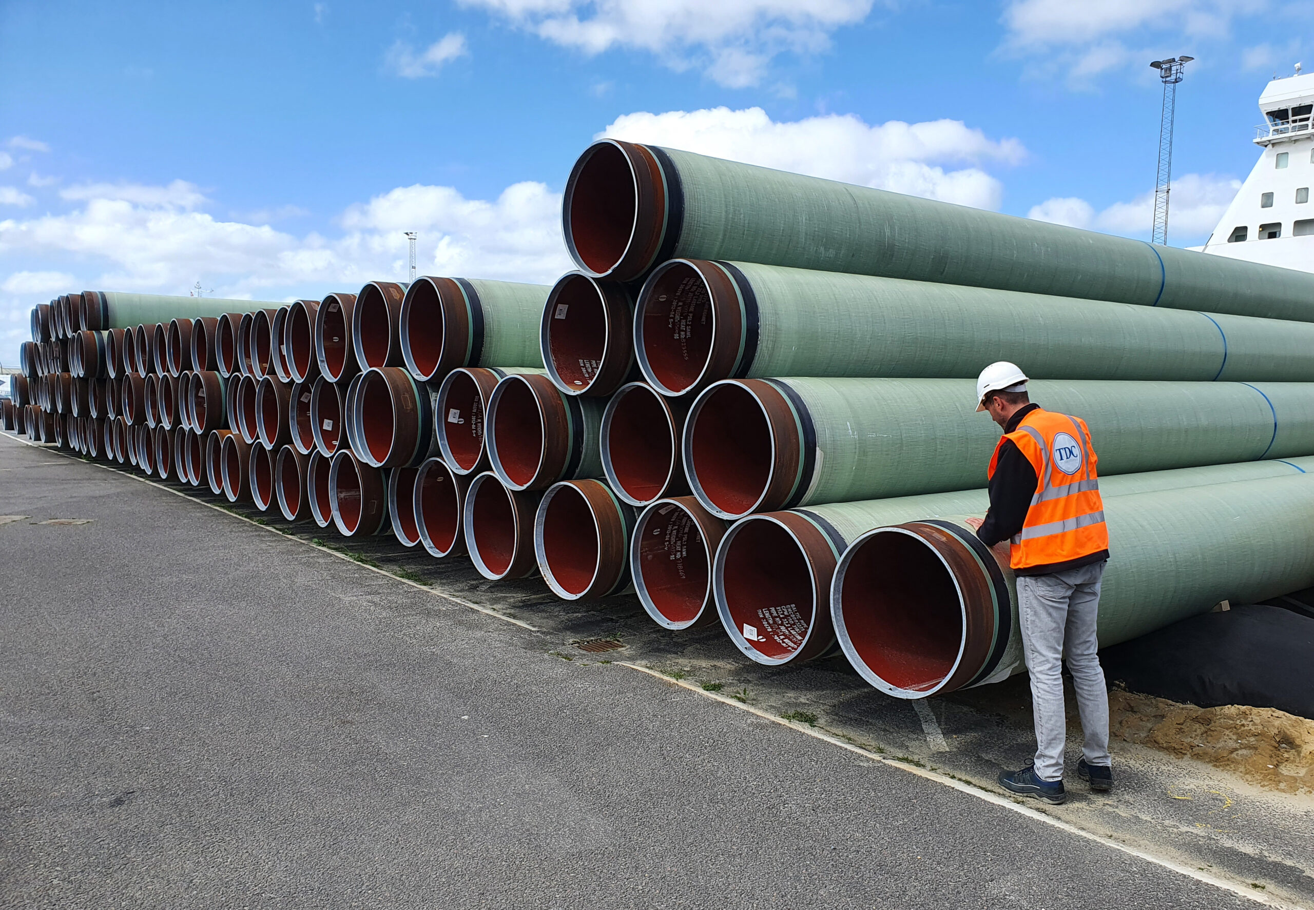 TDC employee quality checking stack of GRP protected pipes at port in Denmark for Baltic Pipe project scaled