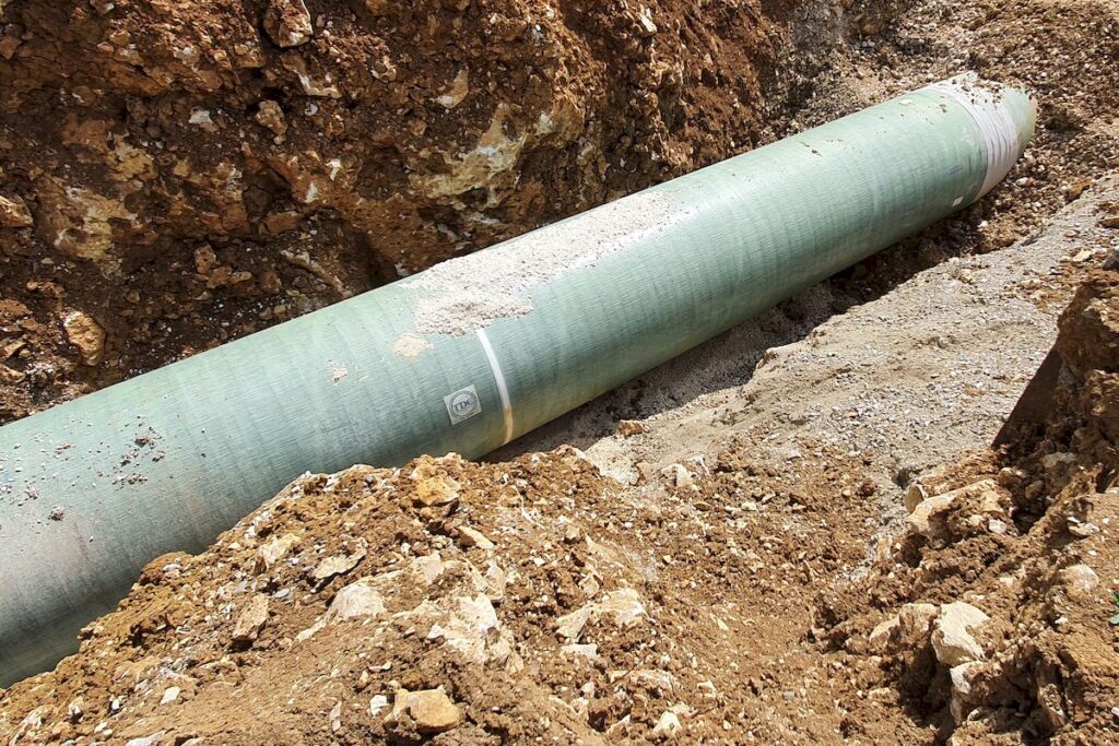 Pipeline with pau wrap OT product in a trench half covered with rocky backfill material